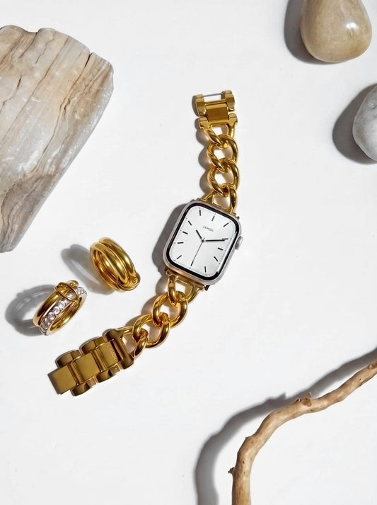 Pre-stacked gold rings beside a gold chain Apple Watch band