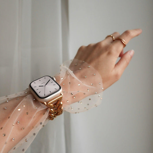 Gold PVD Apple Watch band on wrist under a sheer dotted tulle sleeve