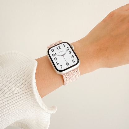Cloud Nylon Apple Watch Band in sakura pink worn on wrist with a white knit sleeve, watch face view
