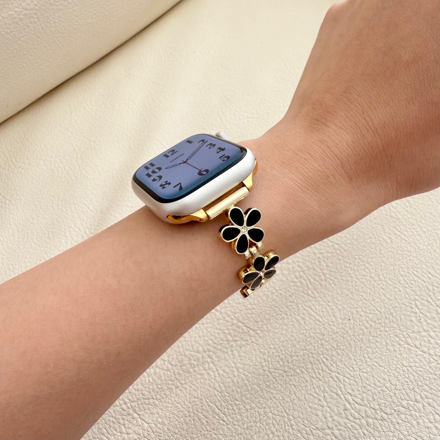 gold APPLE watch bracelet with floral on wrist