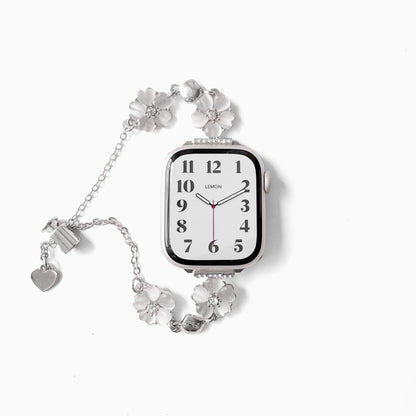 Sakura Chain Apple Watch Bracelet in silver with silver flower links and heart charm beside a watch