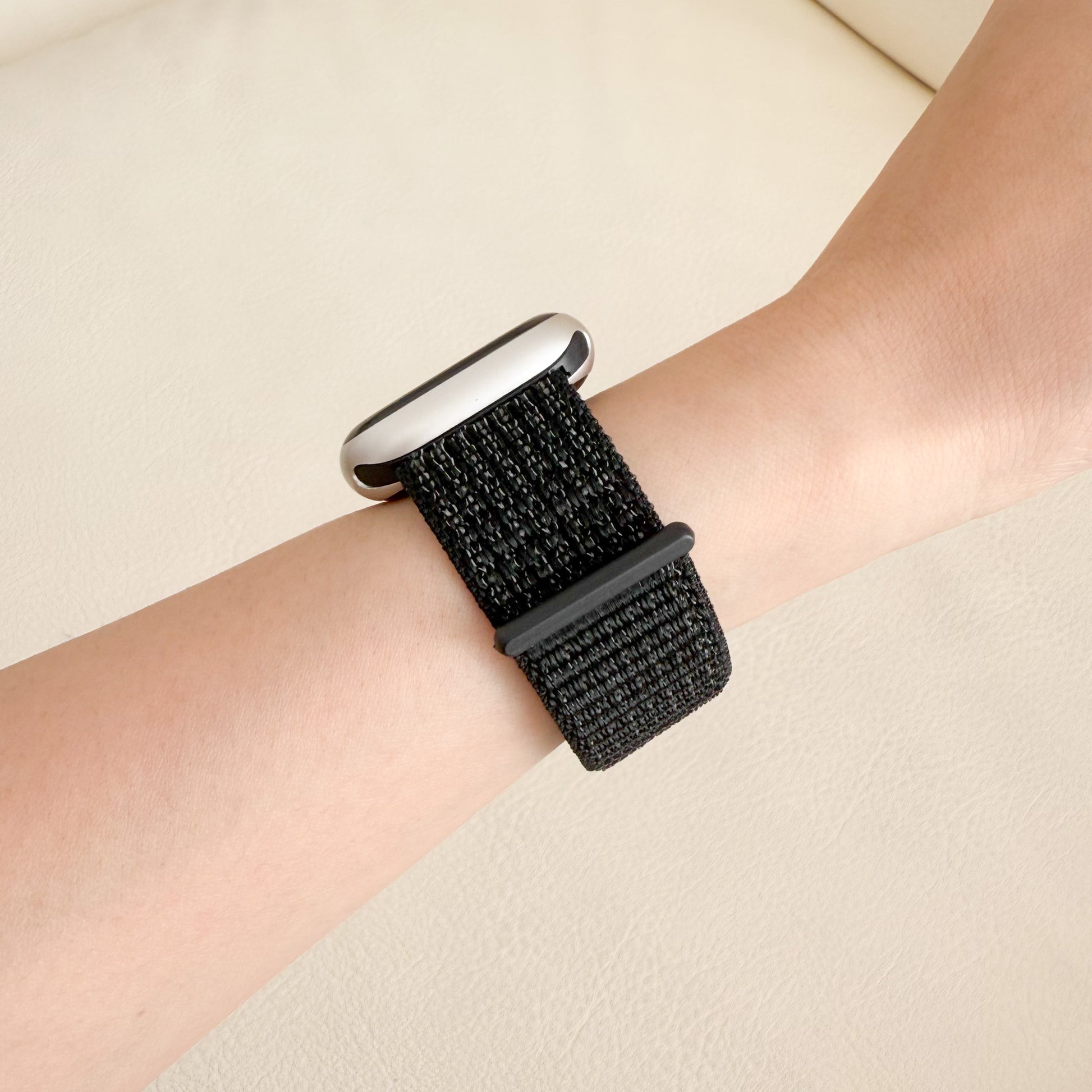 Black woven watch strap on a wrist against a neutral background