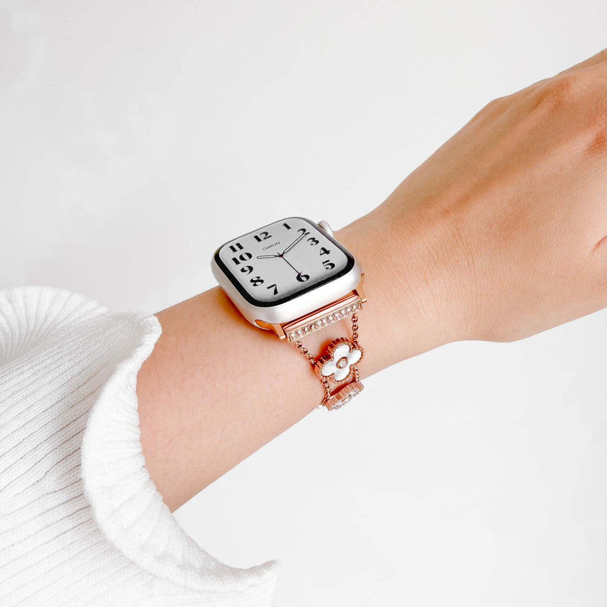 A close-up of a person's wrist wearing a (St-Steel) Flora Chain Apple Watch Bracelet - Rose Gold