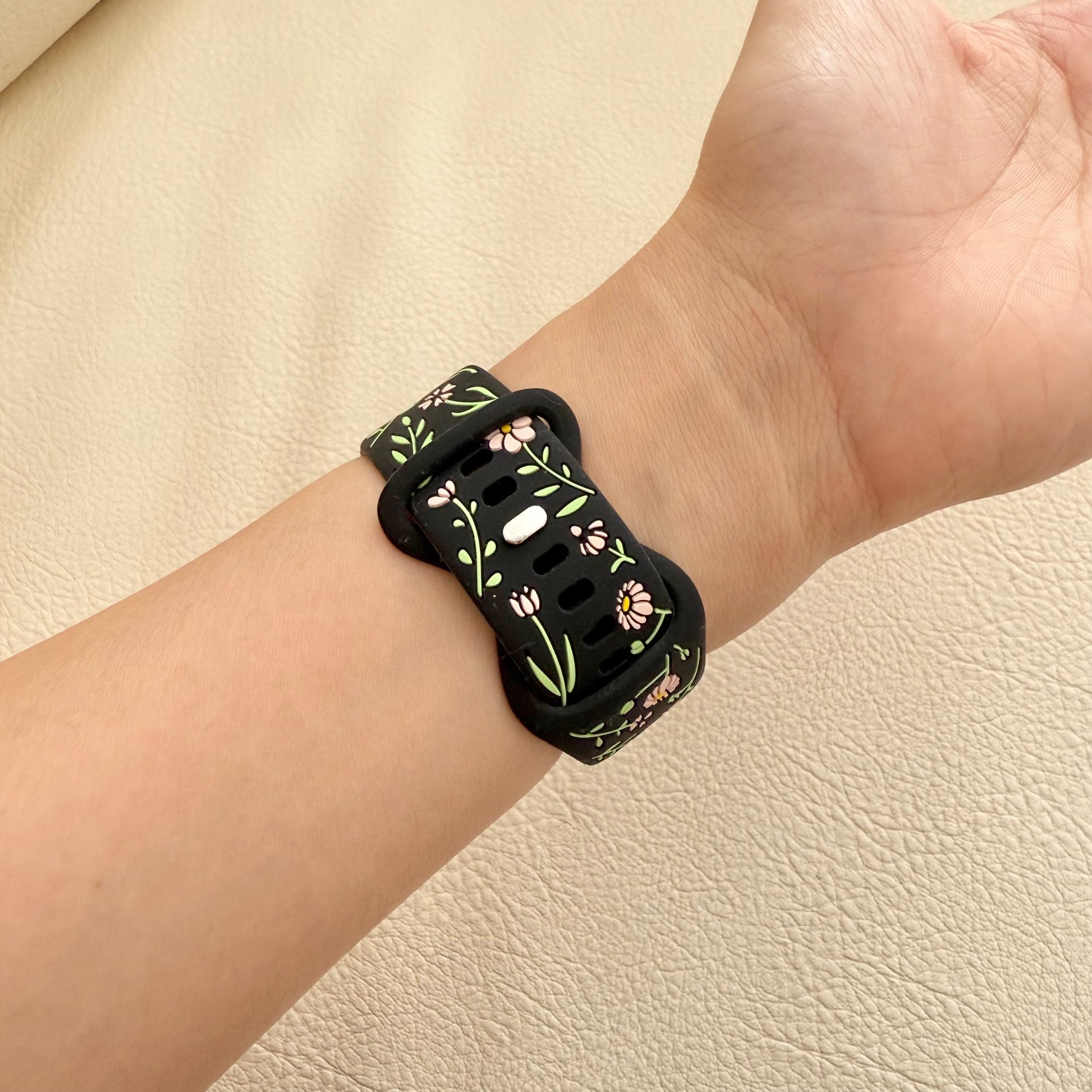 Wrist wearing a black floral-patterned smartwatch band 