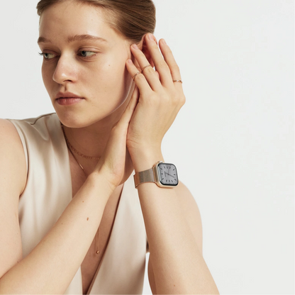 Woman wearing the Slim Milanese Apple Watch Band in rose gold, hand raised near her hair