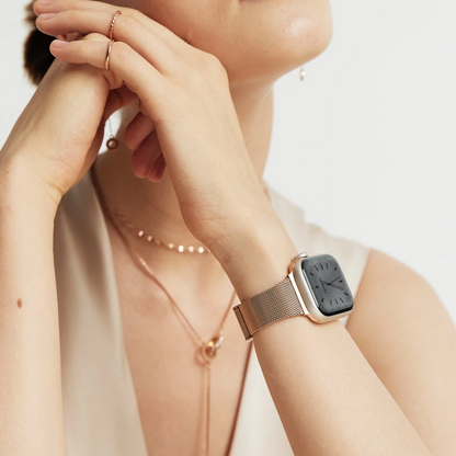 Woman wearing the Slim Milanese Apple Watch Band in rose gold, arms crossed at her collarbone