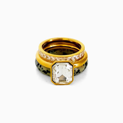 Cookies & Cream Ring Set, a gold-tone ring with an emerald-cut clear rhinestone stacked with a rhinestone row band and a speckled dalmatian jasper band, on a white background