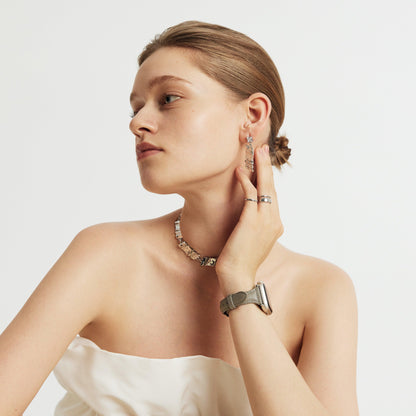 Woman wearing the Classic Leather Apple Watch Band in pearl grey, looking over her shoulder, hair in a bun