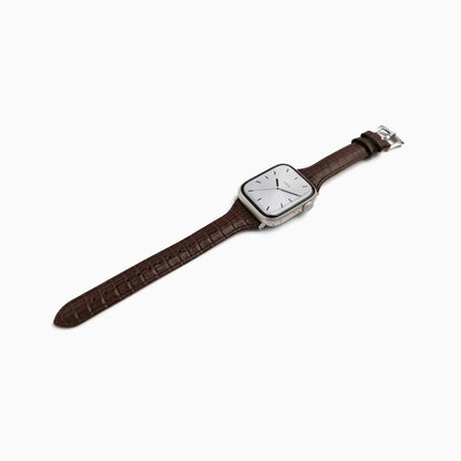Voyage Leather Apple Watch Band in dark brown croc-embossed leather, laid at an angle on white