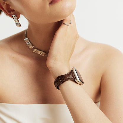 Woman wearing the Voyage Leather Apple Watch Band in brown, hand at her chin with a beaded necklace