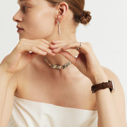 Woman wearing the Voyage Leather Apple Watch Band in brown, hands raised near her chin, looking aside