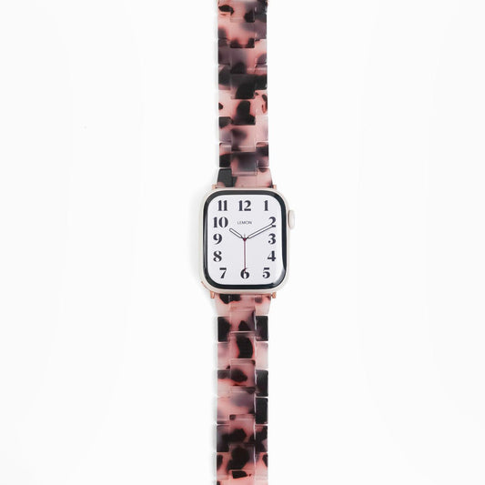 A pink tortoiseshell-patterned resin band for Apple Watch, displayed on a white background.