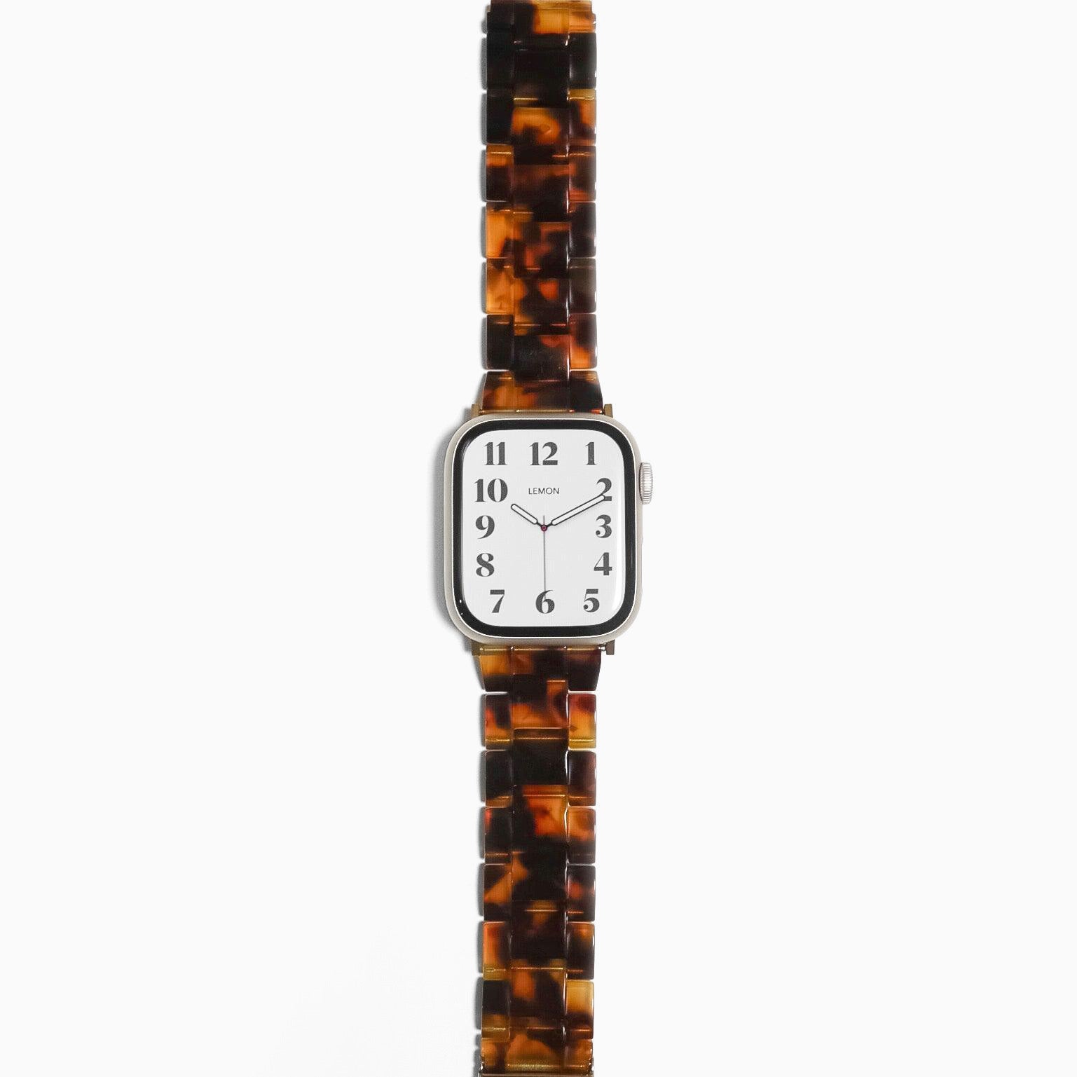 A tortoiseshell-patterned resin band for Apple Watch with a silver metal clasp and watch case.