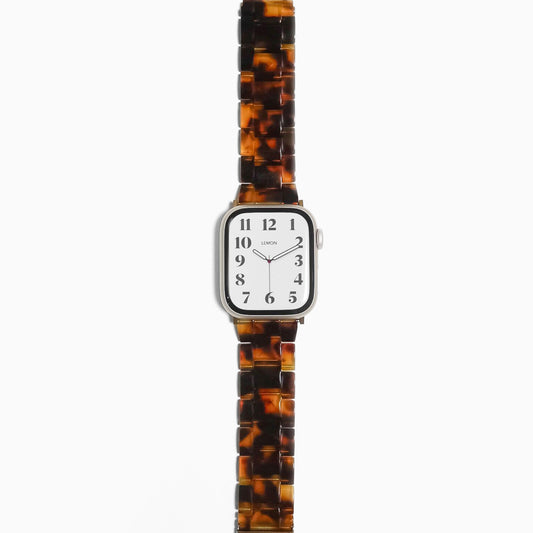 A tortoiseshell-patterned resin band for Apple Watch with a silver metal clasp and watch case.