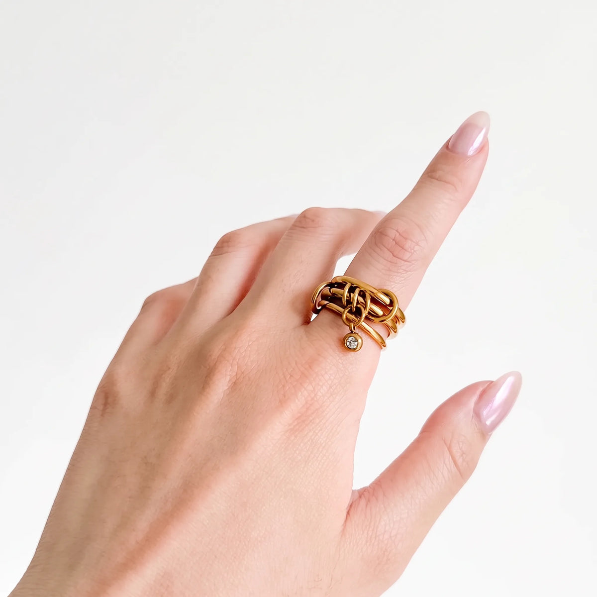 Poppy Charm Ring worn on a woman's hand, gold-tone bands with a crystal drop charm