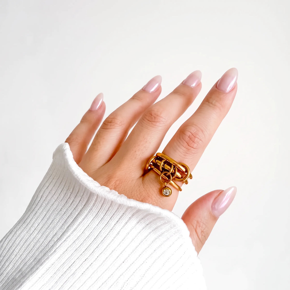 Poppy Charm Ring on a woman's hand with a white ribbed knit sleeve