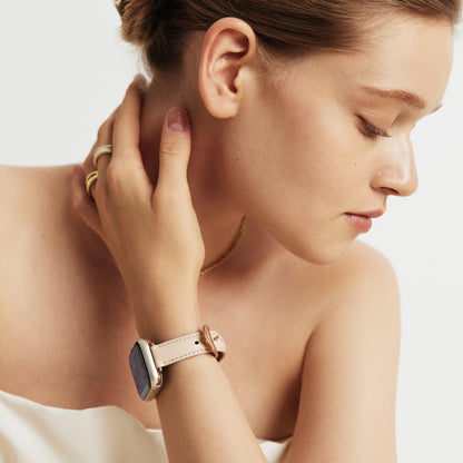 Woman wearing the Rosé Leather Apple Watch Band in pink, hand at her ear, hair in a bun