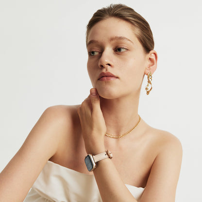 Woman wearing the Rosé Leather Apple Watch Band in pink, hand at her chin, looking down