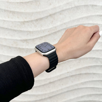 Magnetic Snap Silicone Apple Watch Band in black worn on wrist with a black sleeve, watch face view