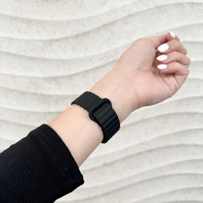 Magnetic Snap Silicone Apple Watch Band in black worn on a raised wrist, side view