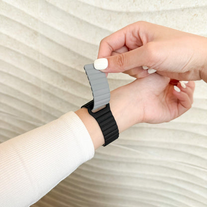 Hand fastening the Magnetic Snap Silicone Apple Watch Band in black and grey on a wrist
