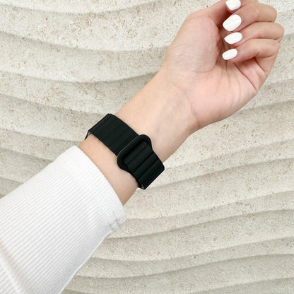 Magnetic Snap Silicone Apple Watch Band in black and grey worn on a raised wrist, side view