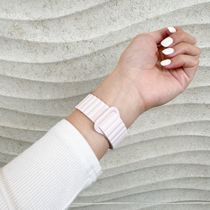 Magnetic Snap Silicone Apple Watch Band in light pink worn on a raised wrist, side view