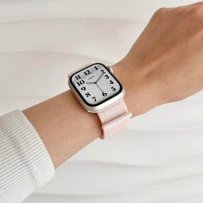 Soft Nylon Apple Watch Loop in light pink worn on wrist with a white knit sleeve, watch face view