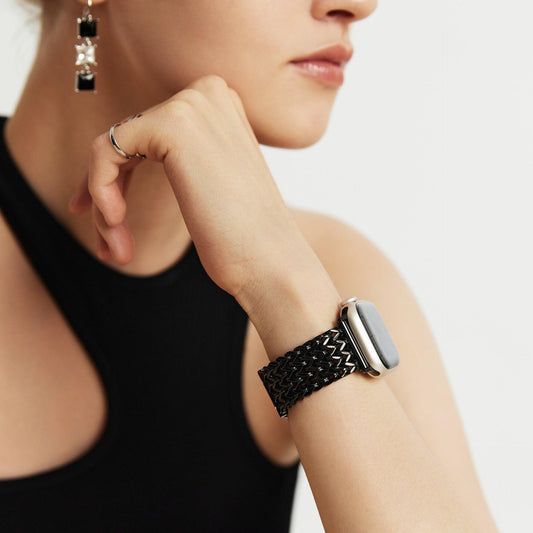 Woman wearing the Infinity Mesh Apple Watch Band in black, wrist raised near her chin in a tank top