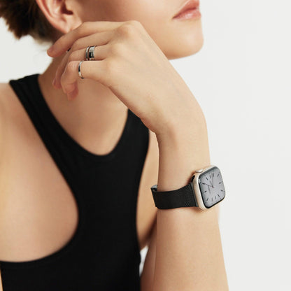 Woman wearing the Slim Milanese Apple Watch Band in black, hand near her neck in a black tank top