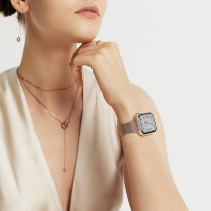 Woman wearing the Slim Milanese Apple Watch Band in rose gold, hand at her chin with layered necklaces