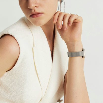 Woman wearing the Slim Milanese Apple Watch Band in silver, hand raised to her face in a cream blazer