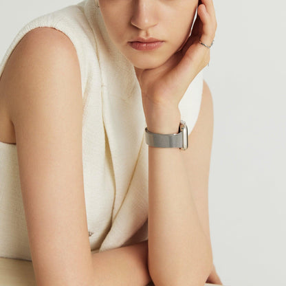 Woman wearing the Slim Milanese Apple Watch Band in silver, hand at her cheek in a cream top