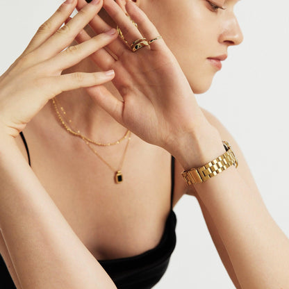 Woman wearing the Slim Oyster Apple Watch Band in gold, hand resting at her neck