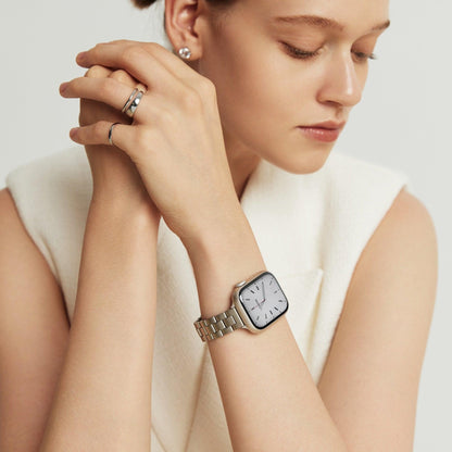 Woman wearing the Slim Oyster Apple Watch Band in silver, hands clasped near her chin in a cream top